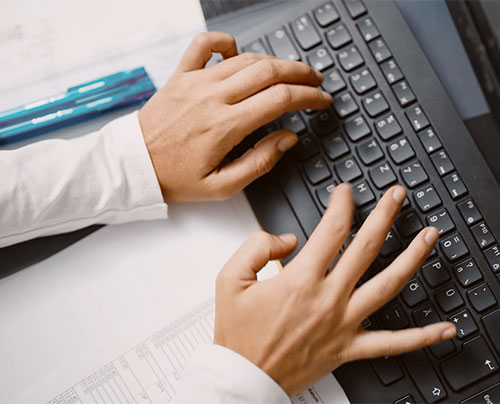 Eine Praxismanagering schreibt auf einer Tastatur